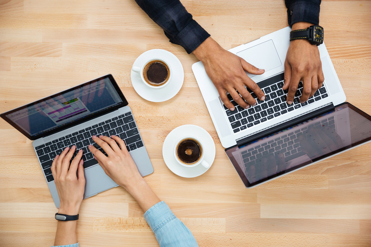 Two people typing on computers