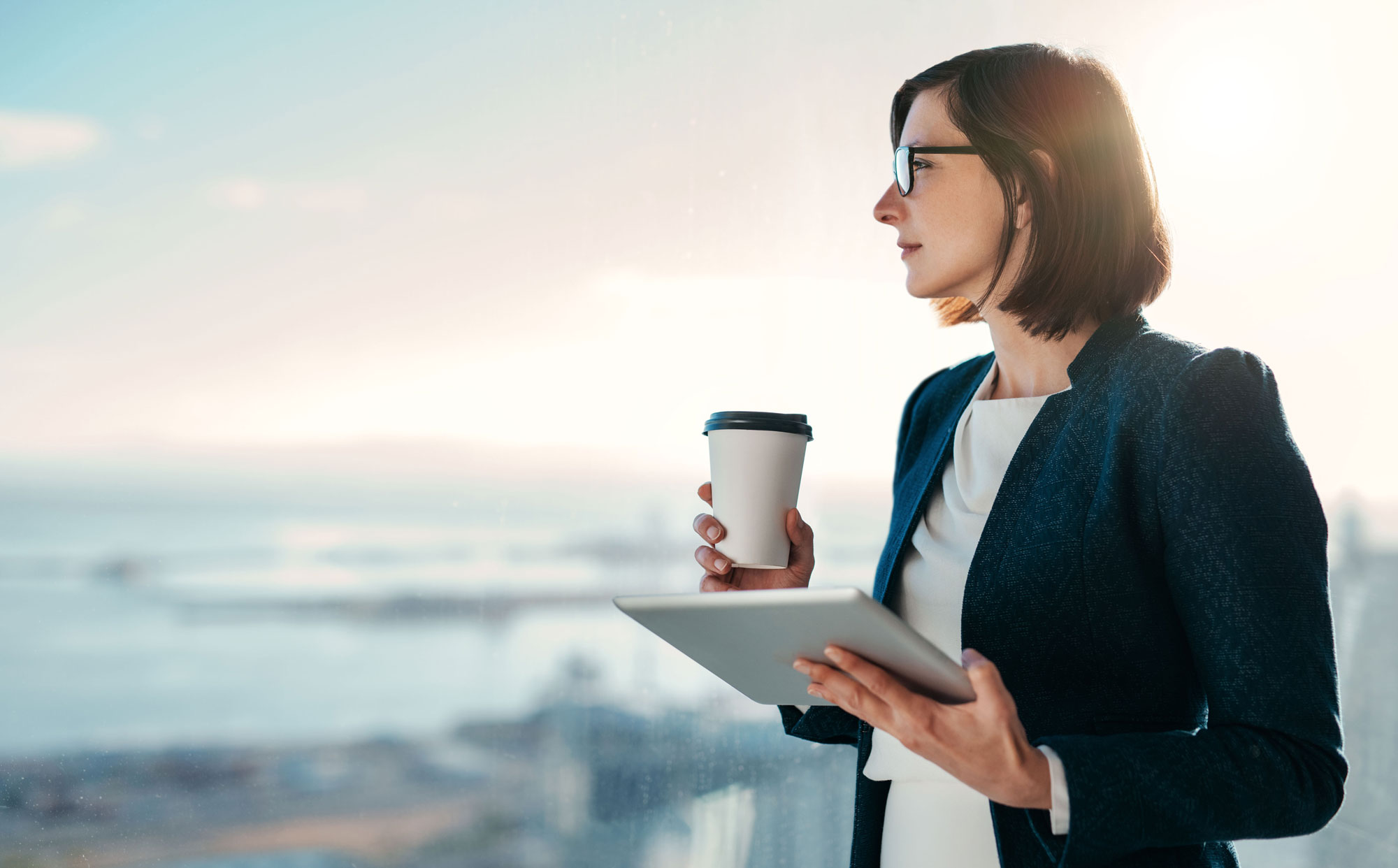 Woman standing with a cup of coffee and a tablet