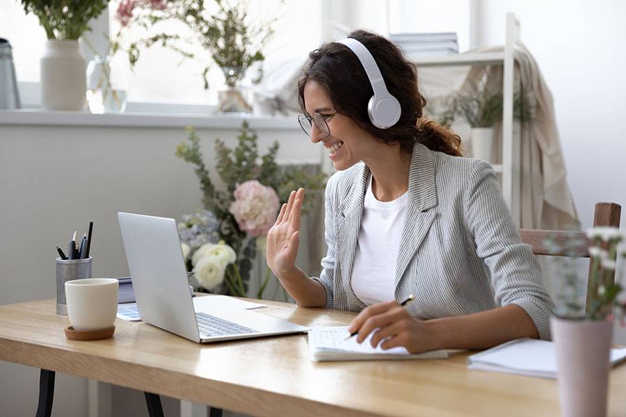 Marketeer with white headphones by her laptop.