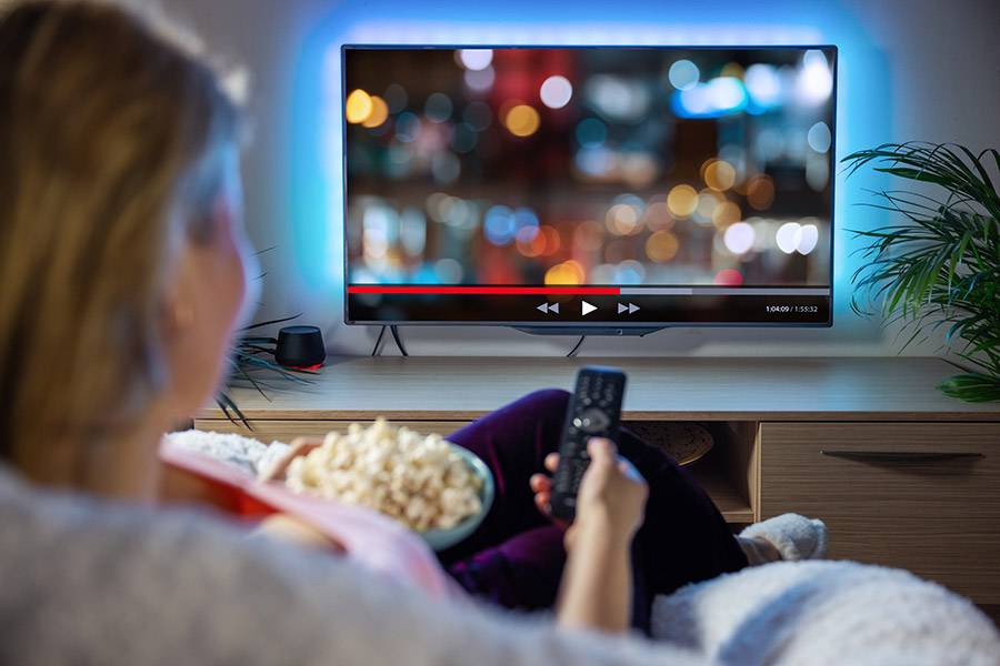 Person eating popcorn and watching a TV.